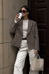 a lady in a white top, a grey jacket and a pair of white pants